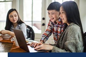 A woman looking at her computer with her two kids