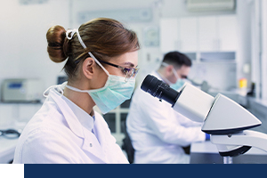 A female scientist is looking into a microscope.